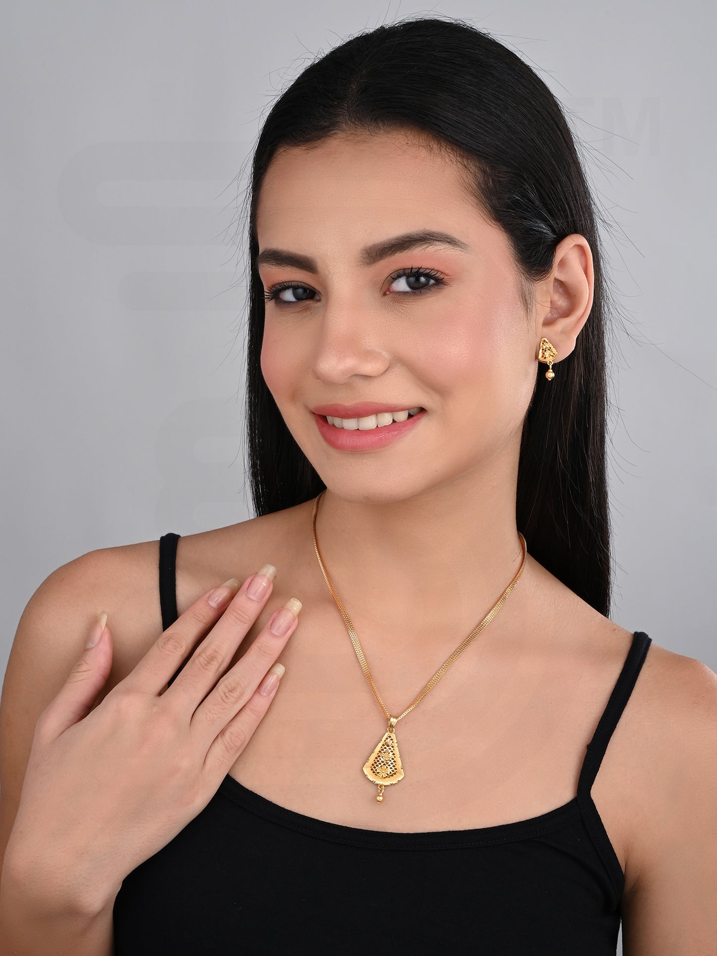 Woman wearing a gold necklace and earrings on a gray background