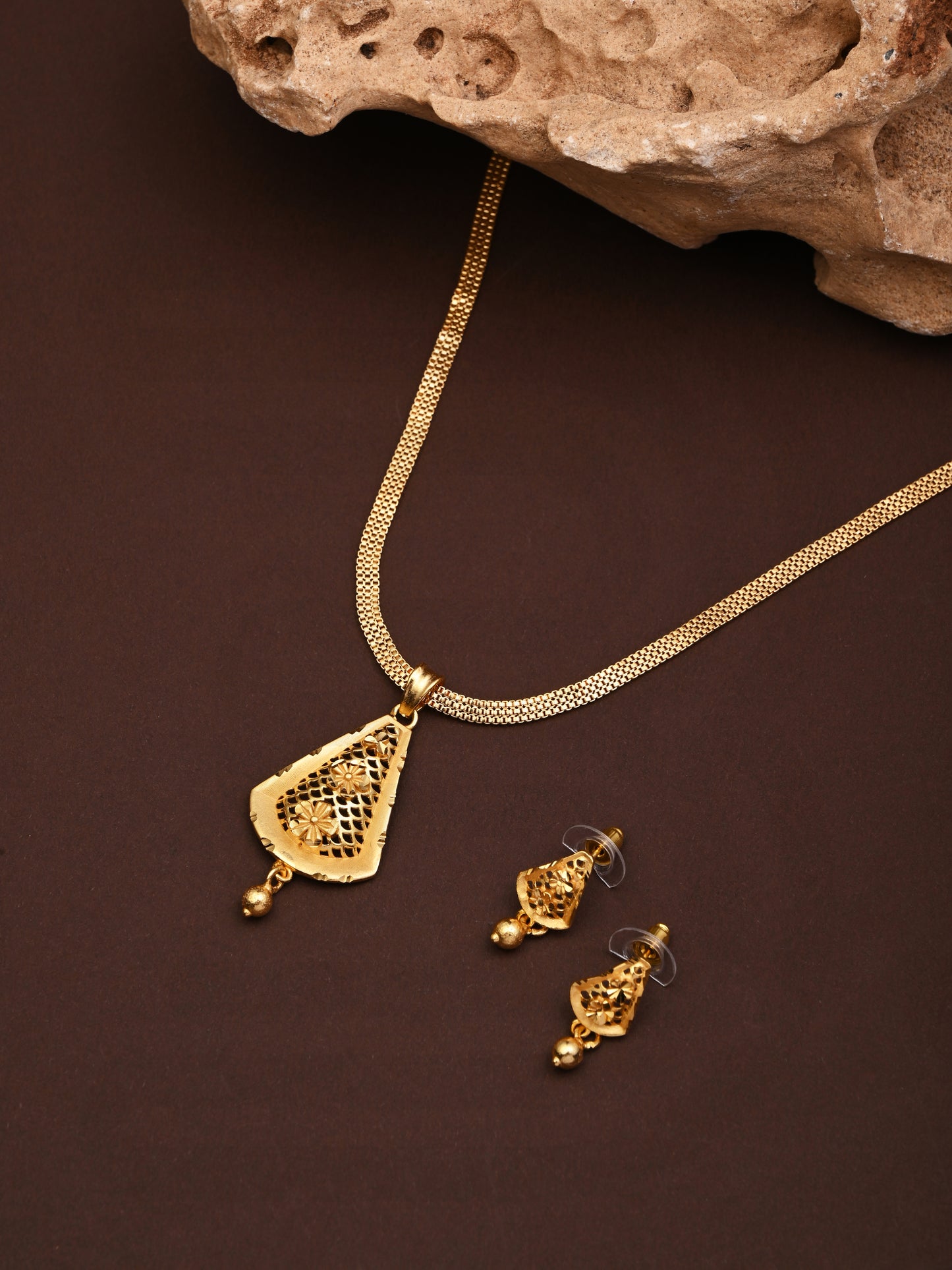 Gold necklace and earrings on a brown background