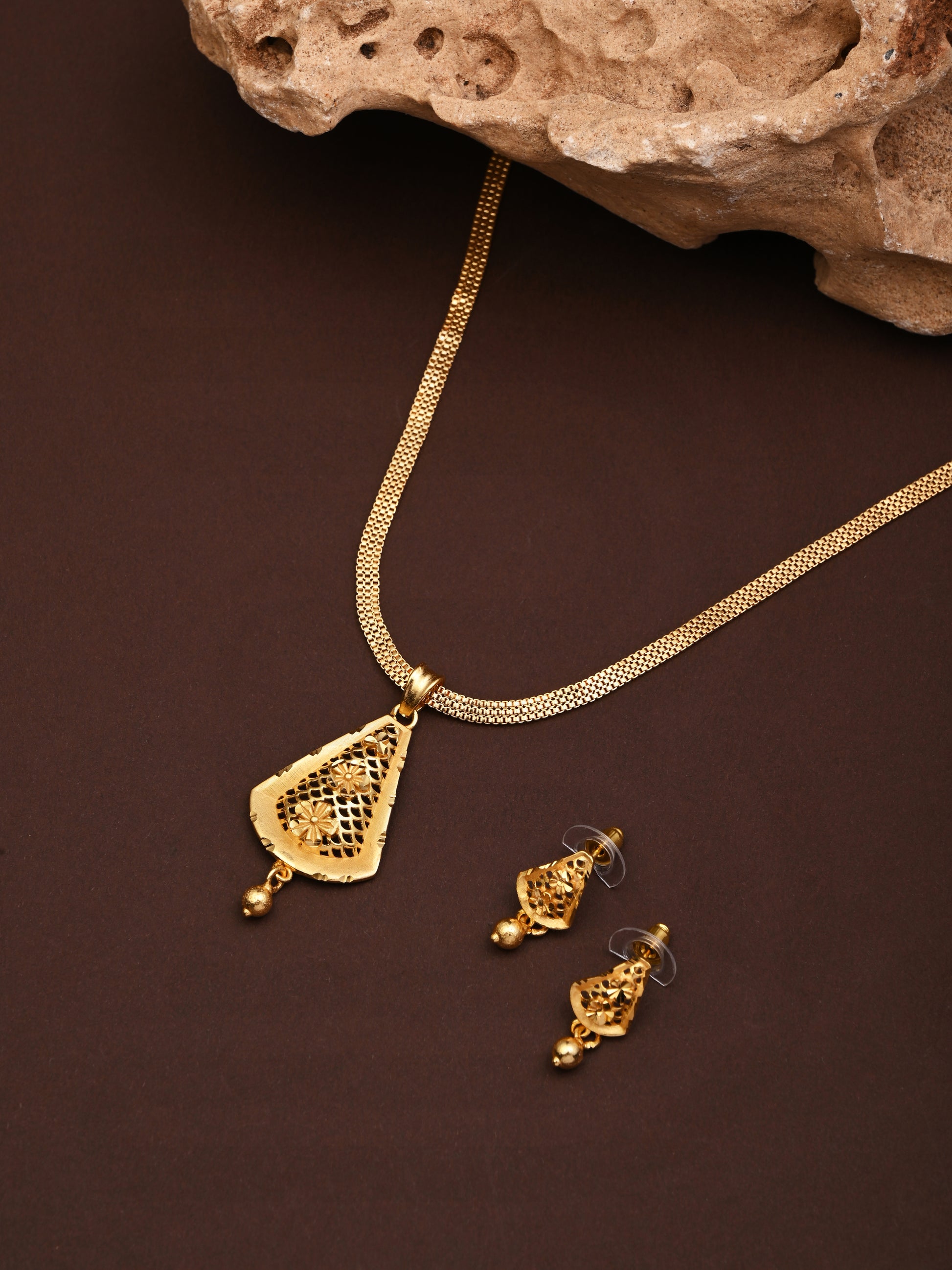 Gold necklace and earrings on a brown background