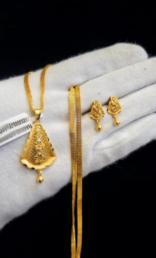 Gold necklace, pendant, and earrings on a white glove with a black background